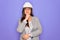 Professional woman engineer wearing industrial safety helmet over pruple background with hand on chin thinking about question,