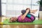 Professional woman exercising and stretching her body doing flexibility exercises, sitting on a yoga mat indoor