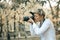 Professional woman photographer taking camera outdoor portraits with prime lens in the photography nature. Greenery tone