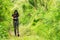 Professional woman photographer taking outdoor with prime lens in the green jungle rain forest nature.