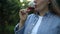 Professional woman sommelier testing red wine in wine glass with tasting and smelling outdoors during sunset in a