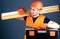 Professional woodworker concept. Man in helmet, hard hat holds toolbox and wooden beams, grey background. Carpenter