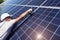 Professional worker installing solar panels on the green metal construction