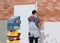 Professional worker lays bricks on the wall using laser level