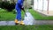Professional worker spray concrete path with special high pressure tool.