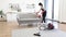 Professional young cleaner vacuuming sofa with portable cordless vacuum cleaner.