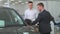 A professional young sales consultant advises a young man about buying a car.