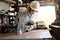 Professional young worker in white uniform and safety equipment cutting a piece of wood on table saw machine in carpentry factory.