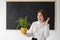 Professor biologist woman in a lesson in front of a blank board. Demonstration of the plant obtained by growing in the