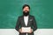 Professor in class on blackboard background. Tutoring. Young bearded teacher near chalkboard in school classroom