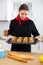 Proffesional woman in chef uniform holding sheet pan with just baked cupcakes