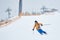 Proficient male skier skiing in snowfall downhill from snow-covered slope with net on edge. Lift station on mountain top