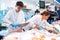 Proficient sellers cutting piece of tuna on tabletop in fish store