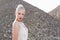 Profile of blonde hair tight up with closed eyes, in white dress, in day time, poses over piles of stones