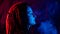 Profile of caucasian girl with dreadlocks smokes a vape in red blue light.