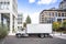 Profile of day cab medium size semi truck with long box trailer unloaded delivered goods to new multi-level apartments in unban