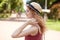 Profile of European romantic attractive young female looking aside, touching her hair with fingers, wearing straw hat and red