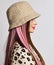 Profile of fashionable young woman with pink colored strands in beige bucket hat and leopard pullover. Side view