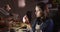 Profile of focused caucasian female jeweller sitting at desk, making jewelry in workshop