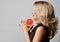 Profile of gorgeous rich blonde woman with healthy silky skin holding half a grapefruit with hands at face. Side view