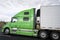 Profile of green big rig semi truck with refrigerated semi trail