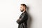 Profile of handsome serious man in leather jacket, looking left, holding hands on chest confident, white background