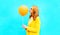 Profile happy woman kisses an air balloon in yellow coat on blue