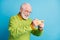 Profile photo of excited grandpa hold cellphone cheerful smiling wear eyeglasses green sweater isolated blue color