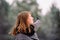 A profile photo of a girl who points her index finger into the distance, looking away. Winter forest background