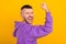 Profile photo of hooray young brunet guy hand fist wear purple hoodie isolated on yellow color background