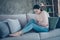 Profile photo of pretty lady suffering from pms holding hands on hurted belly sitting sofa wearing pullover and jeans in