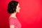 Profile photo of young beautiful wavy curly girl admiring something away from her while isolated with red background