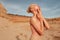 Profile portait of a blonde young woman in splendid slim gold dress posing in desert at the sunset.