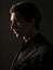 Profile portrait of a confident business man dressed in black stylish suit portrait against a dark background