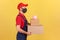 Profile portrait courier in uniform and protective mask holding cardboard parcels with piggy bank on top, save money ordering