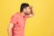 Profile portrait curious bearded man in red striped t-shirt trying to look far away holding hand on forehead, eye vision problems