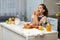 Profile portrait of a funny little girl with curly hair, take breakfast together with mother in the kitchen