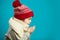 Profile portrait of little girl in red christmas hat, folded her hands together and blowing sideways, isolated shot on