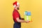 Profile portrait male courier in professional uniform and red santa claus hat holding and giving presents, delivery in holidays