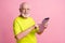 Profile portrait of optimistic pensioner working on tablet wear spectacles green color t-shirt isolated on pastel pink