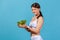 Profile portrait positive healthy woman in white sportswear holding big bowl with fresh vegetable salad, looking at camera with