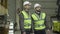 Profile portrait of two Caucasian men standing at warehouse and talking. Employees working at production site. Plant