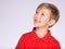 Profile portrait of white smiling kid in a red t-shirt looking away and up.  Photo of a thinking  boy looking away.  Caucasian boy