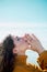 Profile portrait of young adult white female with eyes closed doing namaste gesture and touching her hands in front of blue skies