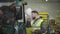 Profile portrait of young bearded caucasian man putting on helmet and talking to his colleague in tow tractor. Workers