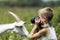 Profile portrait of young blond cute handsome child boy taking picture of funny curious goat looking straight in camera on bright