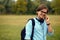 Profile portrait of a young smilig student talking on smartphone, on a public park background, with copy space.