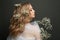 Profile portrait of young woman with blonde curly hairdo and white flowers