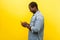 Profile of positive smiley man using cellphone, typing text message or dialing number. isolated on yellow background