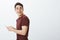 Profile shot of carefree friendly masculine guy in red t-shirt, holding smartphone, turning right with happy smile